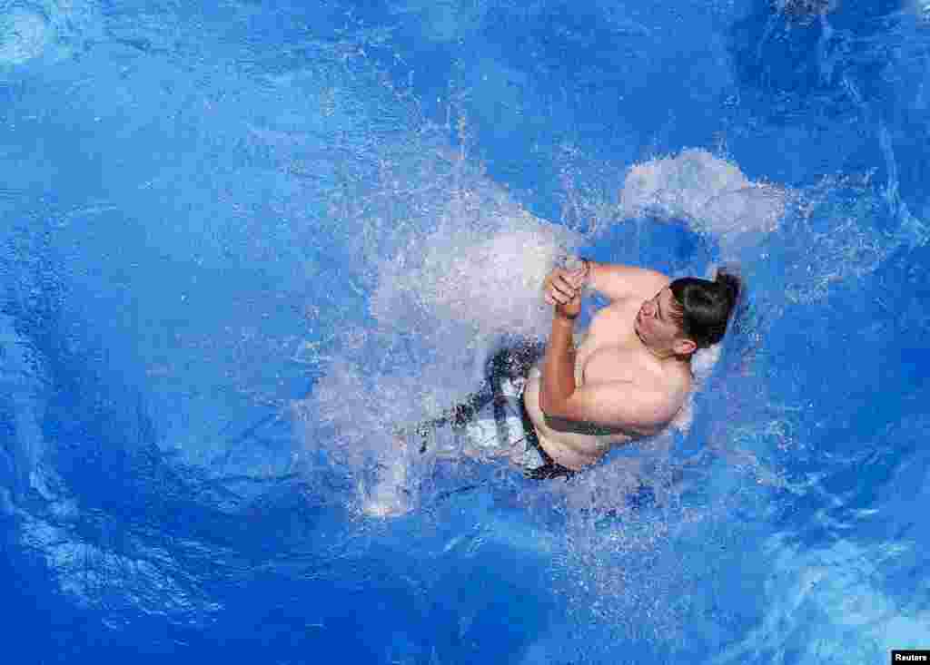 A boy jumps from a 10-meter-high platform into a swimming pool during a hot summer day in Hall in Tirol, Australia. 