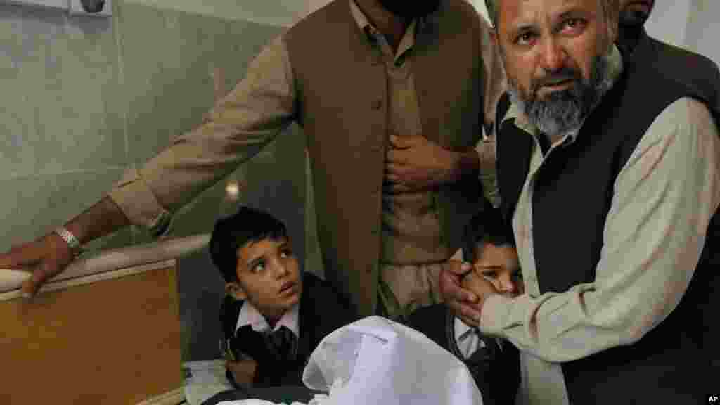 A Pakistani man comforts a student standing at the bedside of a boy who was injured in a Taliban attack on a school, at a local hospital in Peshawar, Pakistan, Tuesday, Dec. 16, 2014.