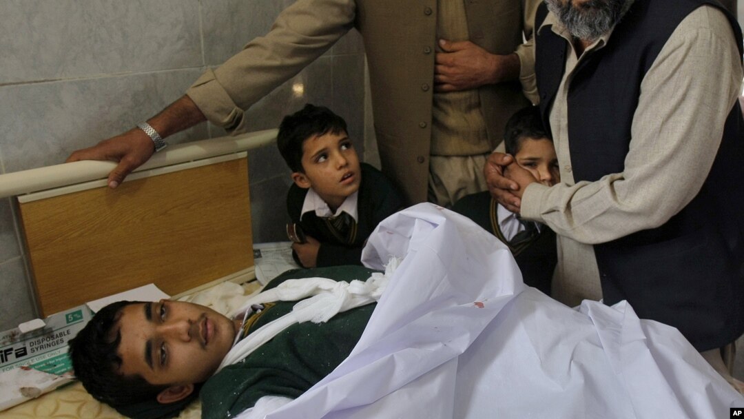 Pria Pakistan menghibur anak-anak sekolah yang menemani rekan mereka yang terluka akibat serangan di Peshawar, Pakistan (16/12).