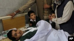 Pria Pakistan menghibur anak-anak sekolah yang menemani rekan mereka yang terluka akibat serangan di Peshawar, Pakistan (16/12).