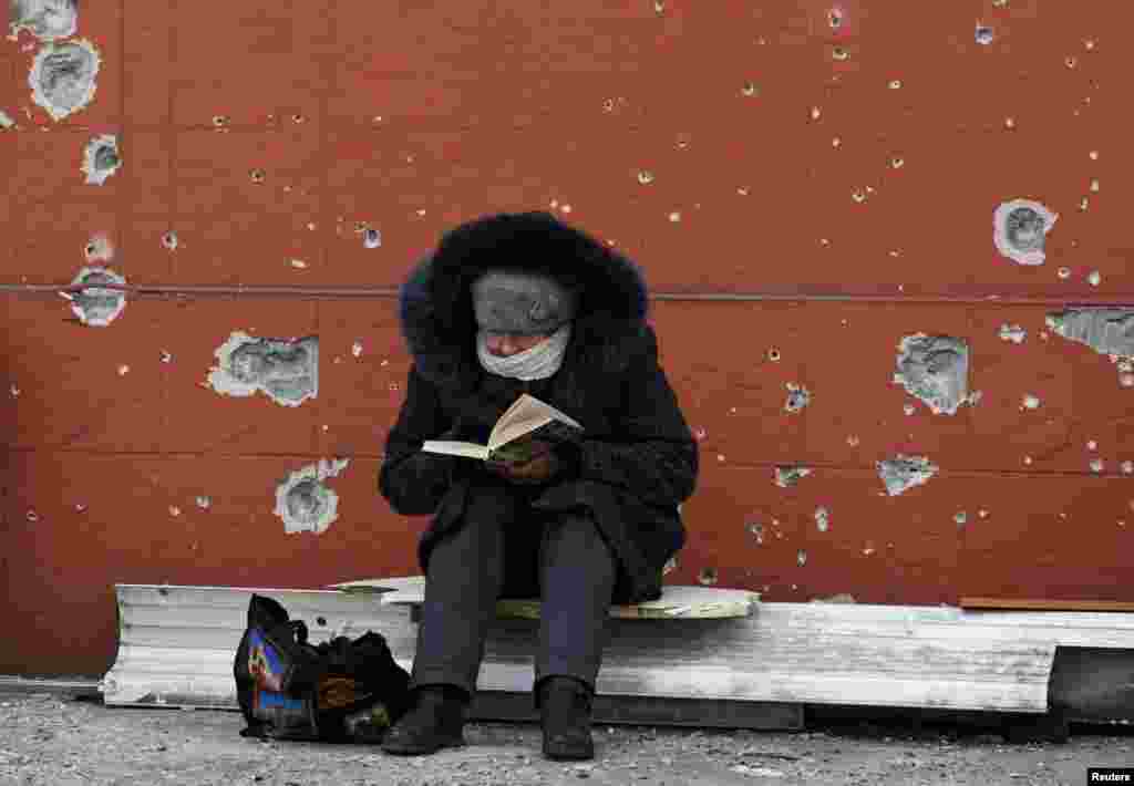 Un residente local lee un libro cerca de un edificio dañado durante el conflicto entre Ucrania y Rusia en la ciudad portuaria sureña de Mariúpol.