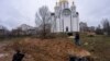 Gazetarët fotografojnë pranë një varri në qytetin Butcha, Ukrainë (3 prill 2022)