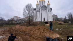 Журналисты фотографируют место массовых захоронений в Буче. 3 апреля 2022 года.