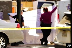 A sheet is used to block the view as the body of one of the people killed in a mass shooting is loaded into a coroner's van In Sacramento, Calif., April 3, 2022.