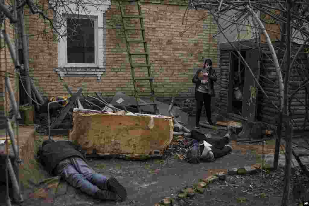 Ira Gavriluk holds her cat as she walks next to the bodies of her husband, brother, and another man, who were killed outside her home in Bucha, on the outskirts of Kyiv, Ukraine.