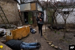 Ira Gavriluk walks next to the bodies of her husband and her brother, who were killed in Bucha, on the outskirts of Kyiv, Ukraine, Monday, April 4, 2022. R (AP Photo/Rodrigo Abd)