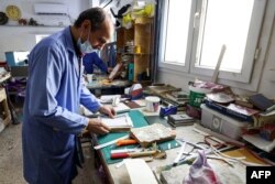 A man assembles pages together to be glued into a volume during a workshop on the restoration of copies of the Holy Koran, Islam's holy book, in Libya's capital Tripoli on March 22, 2022. (Photo by Mahmud Turkia / AFP)