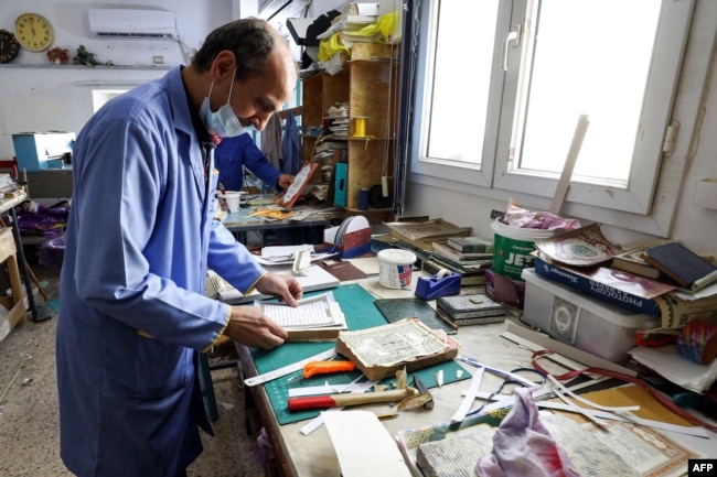 A man assembles pages together to be glued into a volume during a workshop on the restoration of copies of the Holy Koran, Islam's holy book, in Libya's capital Tripoli on March 22, 2022. (Photo by Mahmud Turkia / AFP)