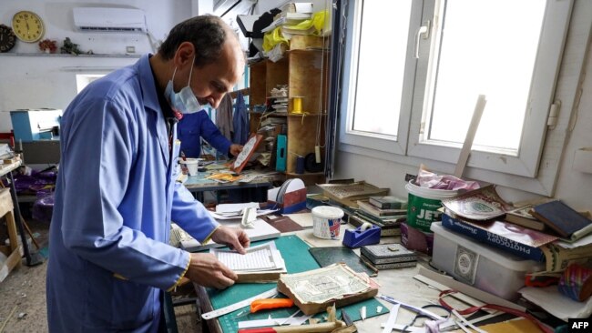 Seorang pria tampak menyusun halaman Al-Quran menjadi satu dalam pelatihan restorasi Al-Quran lama di Tripoli, Libya, pada 22 Maret 2022. (Foto: AFP/Mahmud Turkia)