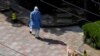 A person in personal protective equipment (PPE) walks a dog at a resident community, as the second stage of a two-stage lockdown has been launched to curb the spread of the coronavirus disease (COVID-19) in Shanghai, China April 3, 2022. 