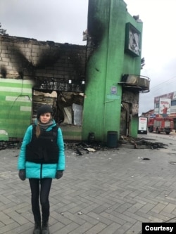 Ukrainian fixer Yulia Zubova stands in front of a building destroyed by Russian forces in the town of Irpin, near Kyiv, April 3, 2022. (Courtesy: Yulia Zubova)
