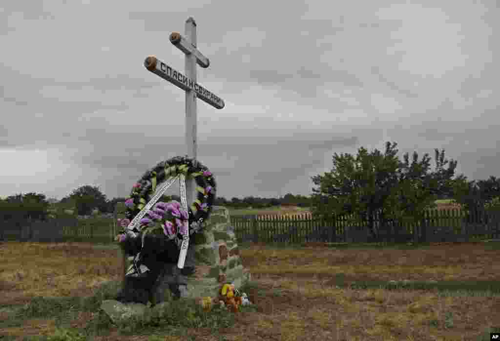A commemorative wreath is laid at the foot of a cross, near the wreckage of Malaysia Airlines Flight 17 seen outside the village of Hrabove, eastern Ukraine, Sept. 9, 2014.