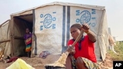 FILE - Mtonga Iliamgee, an internally displaced person at the Guma IDPs camp, prepares flour as the first meal for her family inside the camp in Benue State in north central Nigeria, Jan 6, 2022.