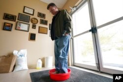 Ryan Bickel walks through a shoe disinfectant as he enters a building at the Blank Park Zoo, April 5, 2022, in Des Moines, Iowa. Zoos across North America are moving their birds indoors and away from people and wildlife as they try to protect them from avian influenza.