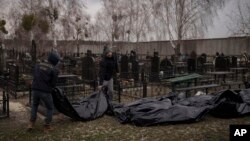 Workers carry the body of people found dead to a cemetery in Bucha, outskirts of Kyiv, Ukraine, April 5, 2022.