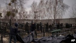 FILE: Workers carry the body of people found dead to a cemetery in Bucha, outskirts of Kyiv, Ukraine. Taken 4.5.2022