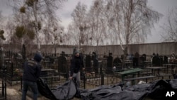 FILE: Workers carry the body of people found dead to a cemetery in Bucha, outskirts of Kyiv, Ukraine. Taken 4.5.2022