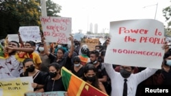 People hold placards as they demand Sri Lanka's President Gotabaya Rajapaksa to resign after his government lost its majority in the parliament, amid the country's economic crisis, during a protest near to a road leading to the parliament building in Colo