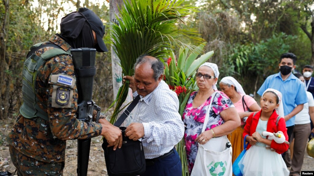 A soldier searches people at a checkpoint in the Distrito Italia neighborhood after El Salvador's Congress approved emergency powers that temporarily suspended some constitutional protections, in Tonacatepeque, El Salvador, April 4, 2022.