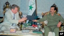 FILE - Russian nationalist Liberal Democratic Party leader Vladimir Zirinovski, left, presents a gift to Iraqi President Saddam Hussein, at Hussein's residency in central Baghdad, Oct. 15, 1995 with the Iraqi flag behind.