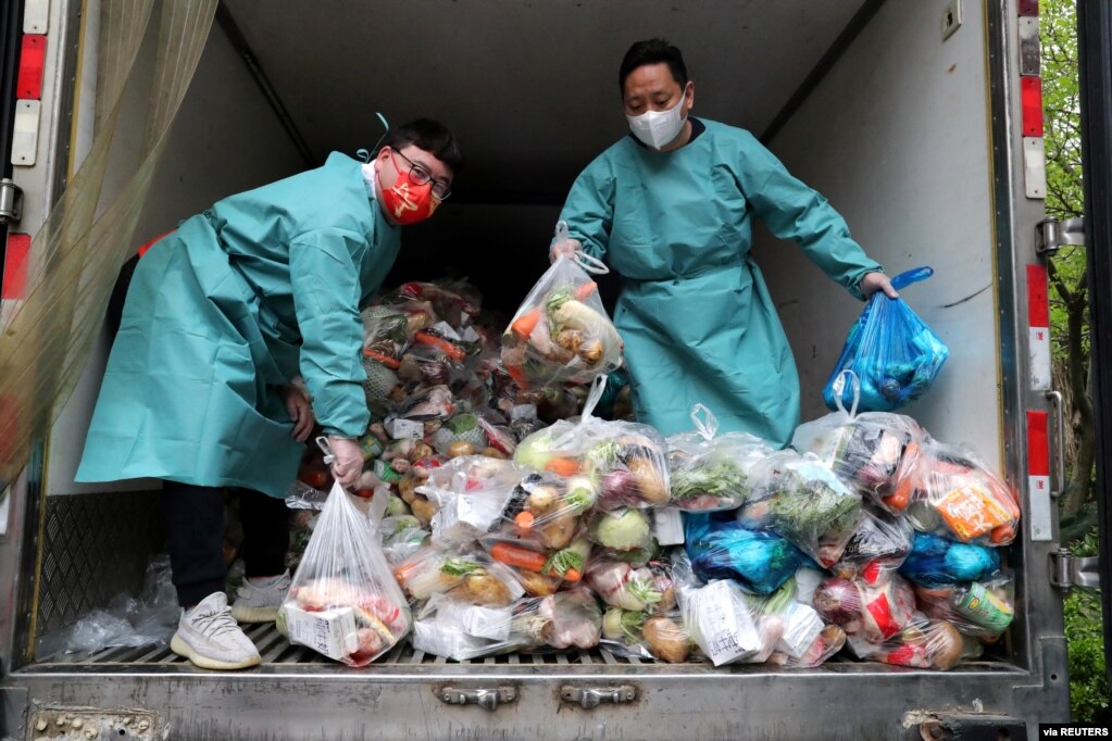 身穿防护服的工作人员把卡车里的蔬菜分发给上海居民。（2022年4月5日）(photo:VOA)