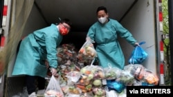 身穿防護服的工作人員把卡車裡的蔬菜分發給上海居民。 （2022年4月5日）