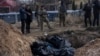 FILE - People stand next to a mass grave in Bucha on the outskirts of Kyiv, Ukraine, April 4, 2022.