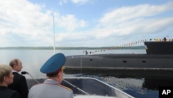 FILE - Russian President Vladimir Putin, left, watches a nuclear submarine off the Northern Fleet to mark the country's Navy Day in Severomorsk, Russia, July 27, 2014. 