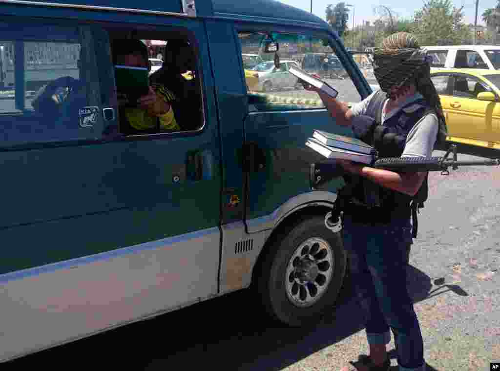A fighter with the Islamic State of Iraq and the Levant distributes a copy of the Quran, Islam's holy book, to a driver in central northern city of Mosul, Iraq, June 22, 2014. 