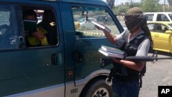 FILE - A fighter with the Islamic State distributes a copy of the Quran, Islam's holy book, to a driver in Mosul, Iraq, June 22, 2014. Islamic scholars in Bangladesh are denouncing activities of the Islamic State.