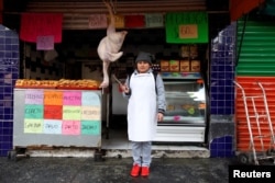 Cristina Alvarez, 29, a butcher, poses for a photograph while standing outside her and her husband's butcher shop, in Mexico City, Mexico, Feb. 25, 2017.