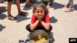 Seorang anak perempuan duduk dengan sepanci nasi yang telah dimasak di kamp Jabalia yang diperuntukkan untuk para pengungsi Palestina di utara Jalur Gaza Strip, pada 13 Juni 2024. (Foto:AFP/Omar Al-Qattaa)
