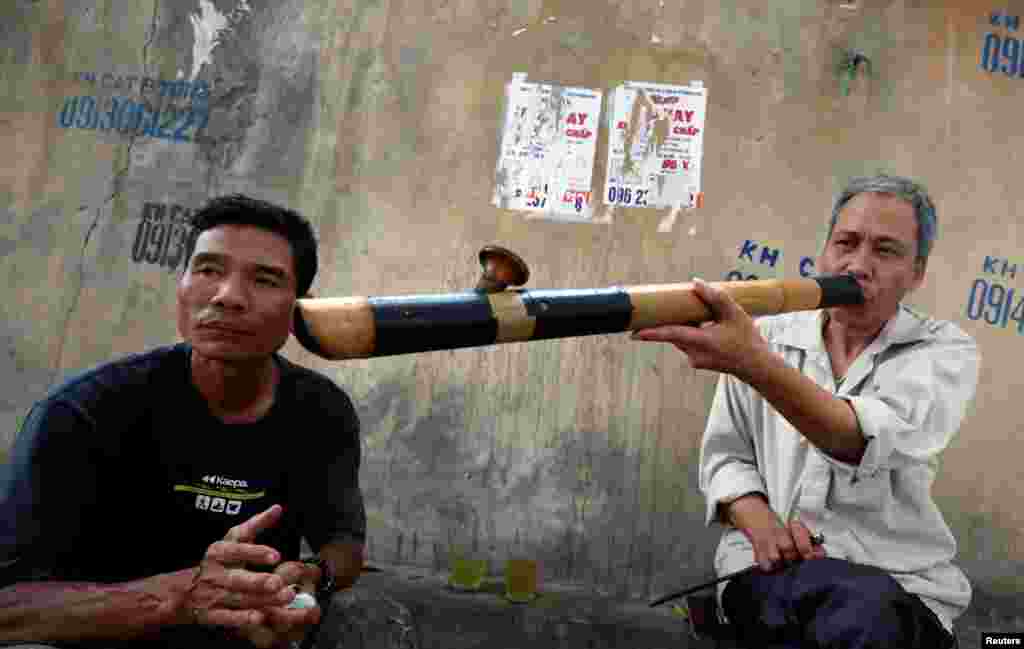 A man smokes a bamboo pipe on a street in Hanoi, Vietnam.