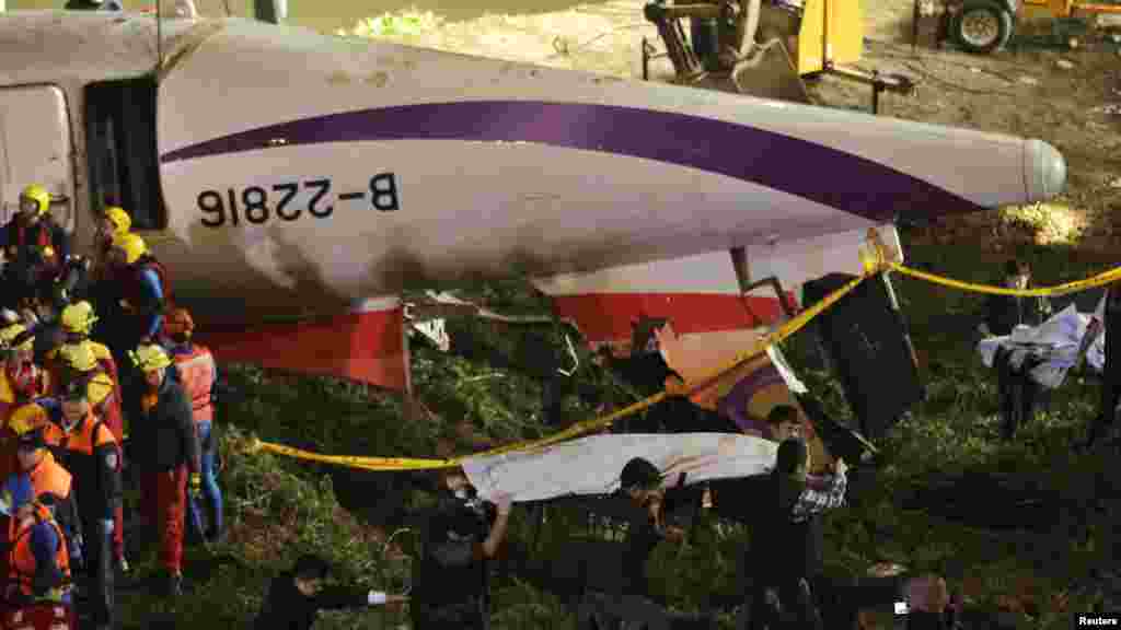 Rescuers carry one body in a bag away after a TransAsia Airways plane crash landed in a river, in New Taipei City.