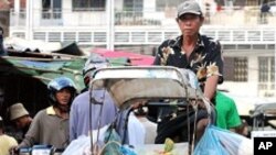 ົຄົນຖີບລົດສາມລໍ້ຂົນສິນຄ້າໄປຂາຍທ່ີຕະຫລາດໃນກຸງພະນົມເປັນ