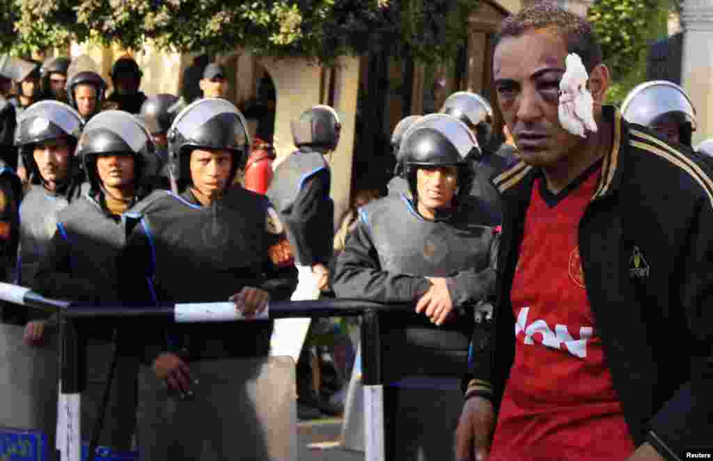 A protester who was injured during overnight clashes between supporters and opponents of Egyptian President Mohamed Mursi, is detained by the Republican Guard in front of the presidential palace in Cairo, December 6, 2012. Egypt's Republican Guard restore