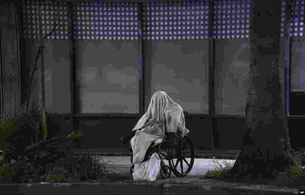 A homeless person sits on a wheelchair on Sunset Blvd. in the Echo Park neighborhood of Los Angeles, April 6, 2020.