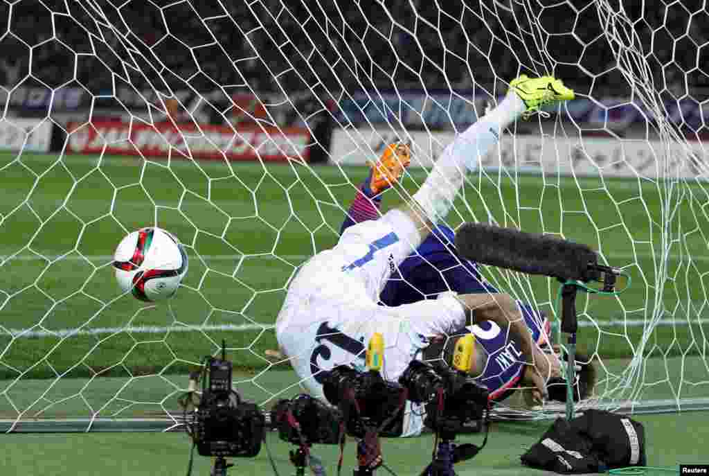 Japan's Shinji Okazaki (R) and Uzbekistan's Lutfulla Turaev dive into the net after Japan's Gaku Shibasaki (not in picture) scored during their international friendly soccer match in Tokyo.