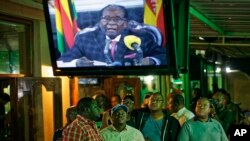 Zimbabweans watch a televised address to the nation by President Robert Mugabe at a bar in downtown Harare, Zimbabwe, Nov. 19, 2017.