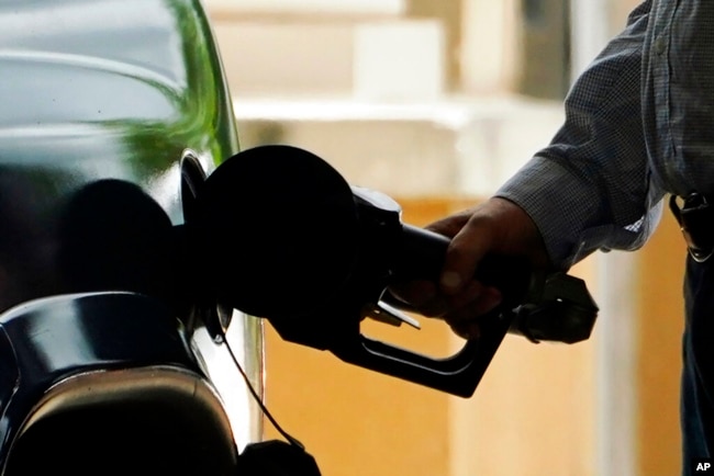 FILE- A customer pumps gas into his vehicle at a Sam's Club in Madison, Miss., May 24, 2022.