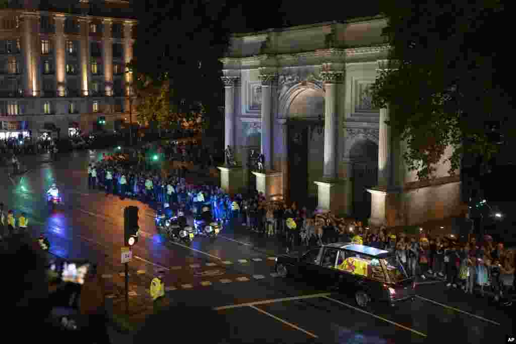 People gather near the Marble Arch as the State Hearse carrying the coffin of Queen Elizabeth II drives from RAF Northolt to Buckingham Palace in London, Sept. 13, 2022.