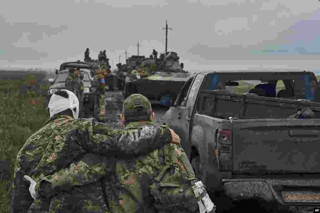 A Ukrainian soldier helps his wounded fellow soldier while military vehicles move on the road in the freed territory of the Kharkiv region, Sept. 12, 2022.&nbsp;Ukrainian troops retook a wide swath of territory from Russia, pushing Russian troops all the way back to the northeastern border in some places, and claiming to have captured many Russian soldiers.