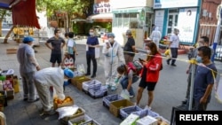 Sejumlah pembeli berdiri di belakang garis pembatas di sebuah kios buah di tengah merebaknya kasus Covid-19 di distrik Tianshan, di Urumqi, Wilayah Otonomi Xinjiang Uyghur di China, 5 September 2022. (Foto: sumber lain via Reuters)