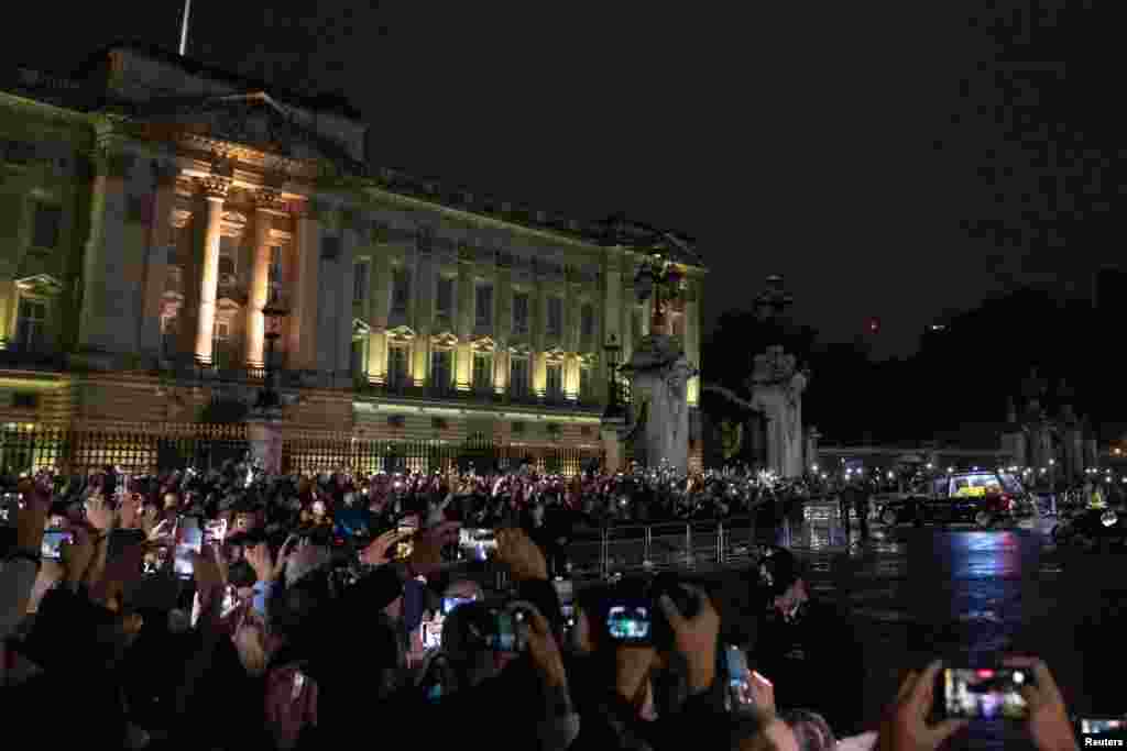 Los espectadores alzan sus teléfonos para captar el momento en que el coche fúnebre que lleva el ataúd de la reina Isabel llega al Palacio de Buckingham, en Londres, el 13 de septiembre de 2022.