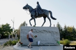 FILE PHOTO: Breton Cousins brings flowers to a statue of Queen Elizabeth II near Rideau Hall, after Queen Elizabeth, Britain's longest-reigning monarch and the nation's figurehead for seven decades, died aged 96, in Ottawa, Ontario, Canada, September 8,
