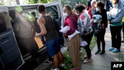 Des migrants du Venezuela, qui sont montés à bord d'un bus au Texas, attendent d'être transportés vers une église locale par des volontaires après avoir été déposés devant la résidence du vice-président américain Kamala Harris.