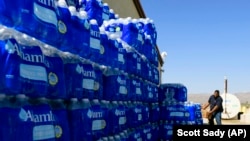 FILE- Tommy Gutierrez, Paiute, helps load water bottles that are distributed weekly to the Yerington Paiute tribe in Yerington, Nev.