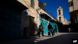 FILE - Palestinians walk past closed stores near the Church of the Nativity, in the West Bank City of Bethlehem, Nov. 23, 2020. UNCTAD reports in September 2022 that the Palestinian economy is still reeling under the impact of COVID-19.