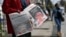 Pedestrians walk past a vendor selling local dailies carrying the headlines reporting the news of the death of Queen Elizabeth II, in Nairobi on Sept. 9, 2022.