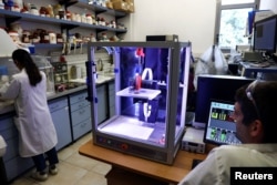 Printer 3D membentuk objek datar menggunakan tinta kayu yang dikembangkan oleh ilmuwan Israel dari Hebrew University of Jerusalem, di Yerusalem, 6 September 2022. Kayu pipih tersebut akan mengeras setelah dikeringkan, dan melengkung menjadi objek 3D. (REUTERS/Ronen Zvulun)